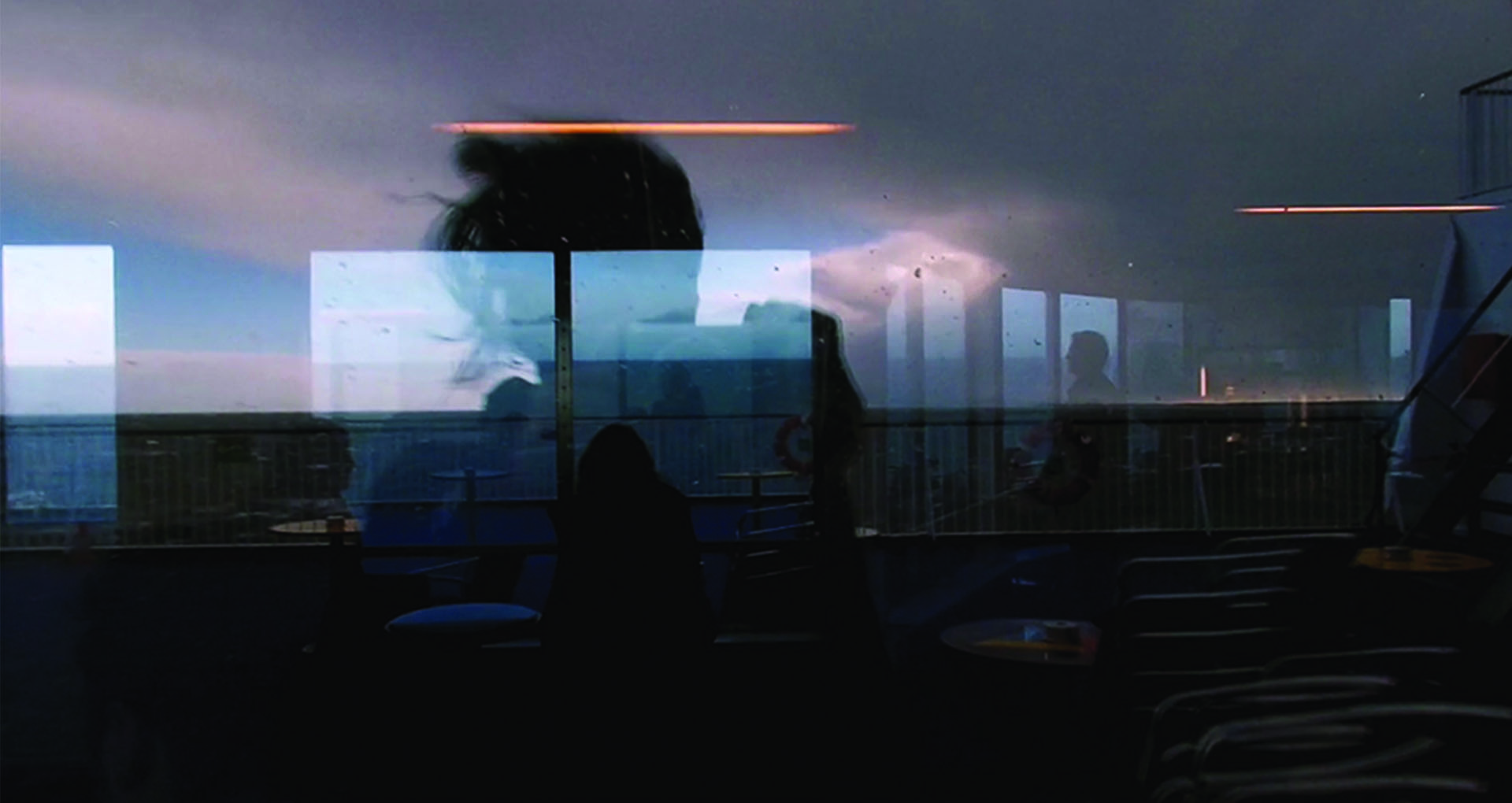 Color photography. Backlit reflection of a woman in daylight on the deck of a boat.