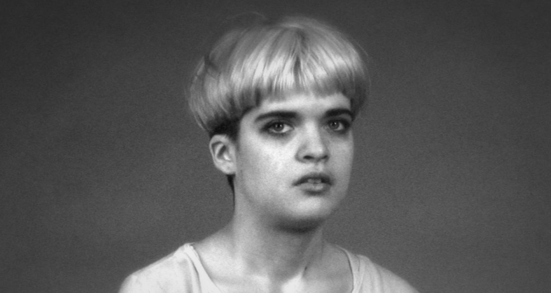 Photo en noir et blanc. Une jeune fille avec les cheveux courts et décolorés