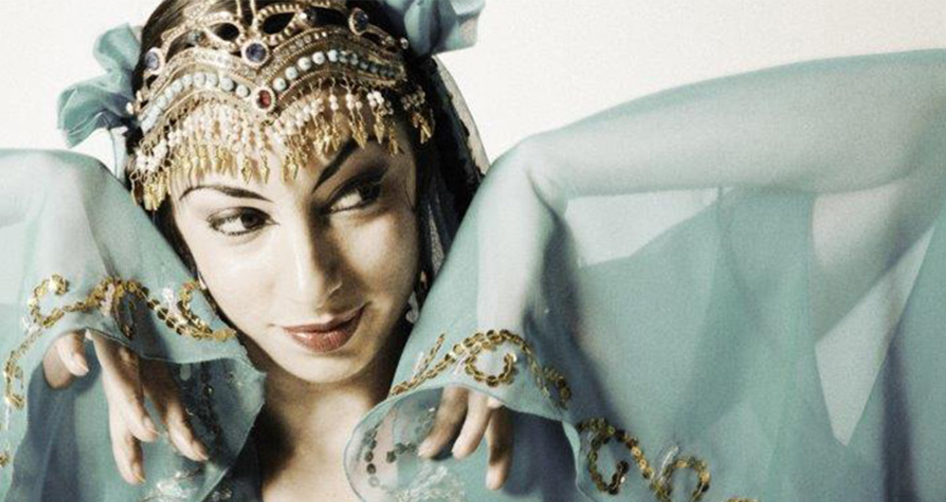 ©Miriam Peretz Une danseuse en habit traditionnel indien. Une couronne de bijoux sur la tête et un voile vert transparent sur les épaules et les mains.