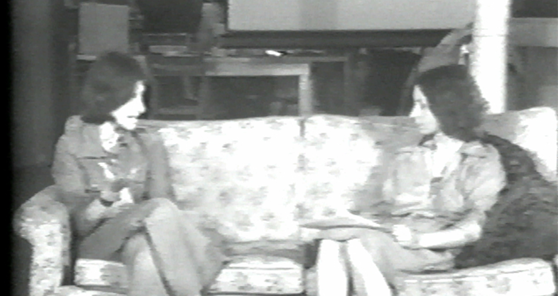Image vidéo en noir et blanc. 2 femmes assises sur un canapé
